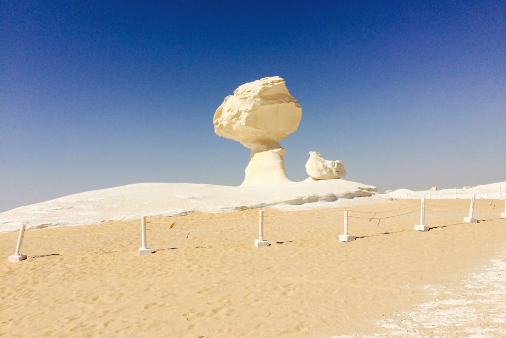 A striking rock formation in Egypt's White Desert under a blue sky.