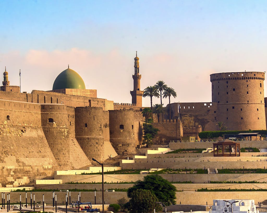 Ancient citadel with minarets and dome in a sunny cityscape setting, showcasing rich architecture.