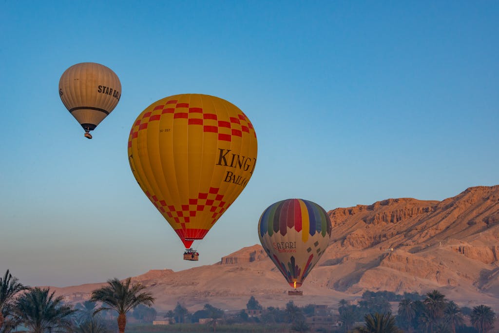 Colorful hot air balloons soar over Luxor's scenic desert landscape at sunrise.