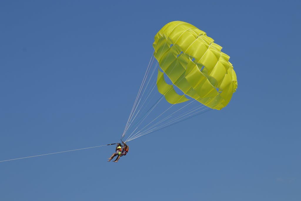 Experience the thrill of parasailing with a vibrant yellow parachute against a clear blue sky.