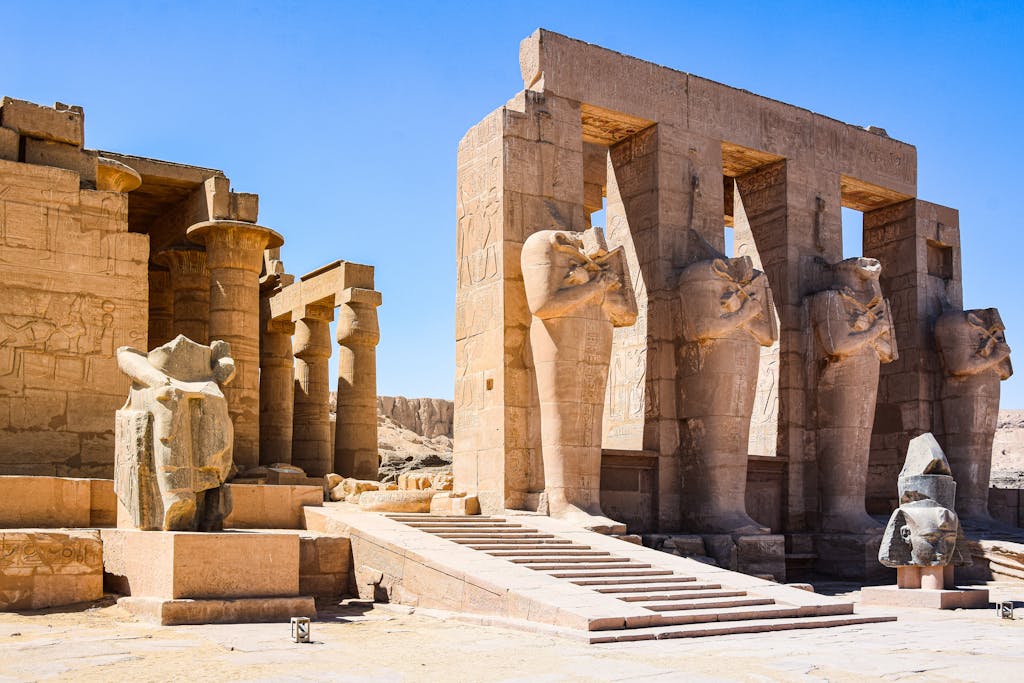 Explore the ancient ruins of Medinet Habu Temple in Egypt, showcasing impressive stone statues and columns.