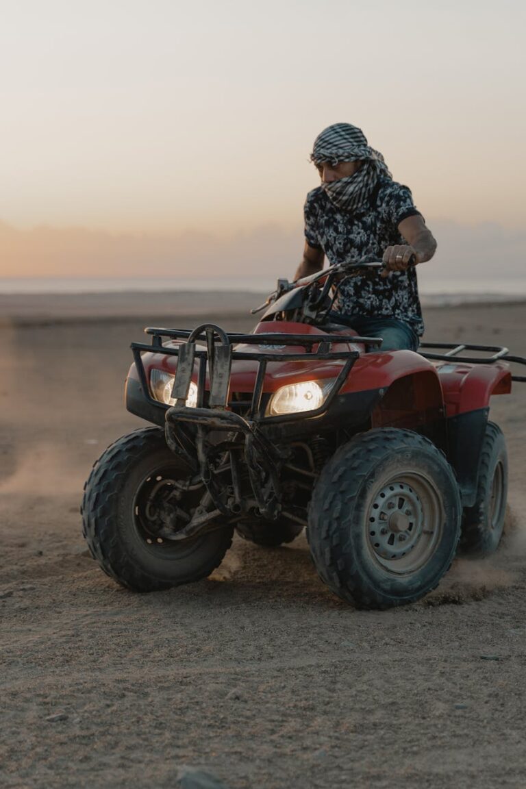 a man driving an atv on the desert sand