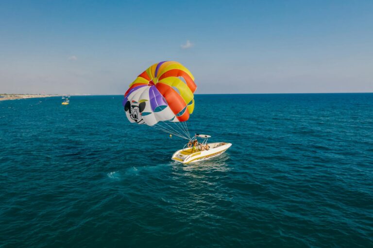 tourists deploying a parachute for parasailing while sailing on a motorboat