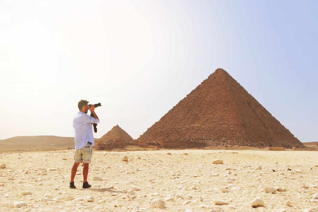 Photographer taking a picture of the Pyramid of Giza under the bright Egyptian sun.