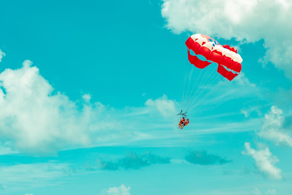 Thrilling paragliding experience in Cancún, Mexico with vibrant blue skies and fluffy clouds.