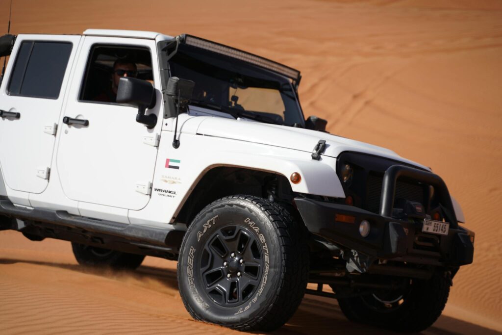 White Jeep Wrangler traversing desert dunes showcasing a thrilling off-road adventure.