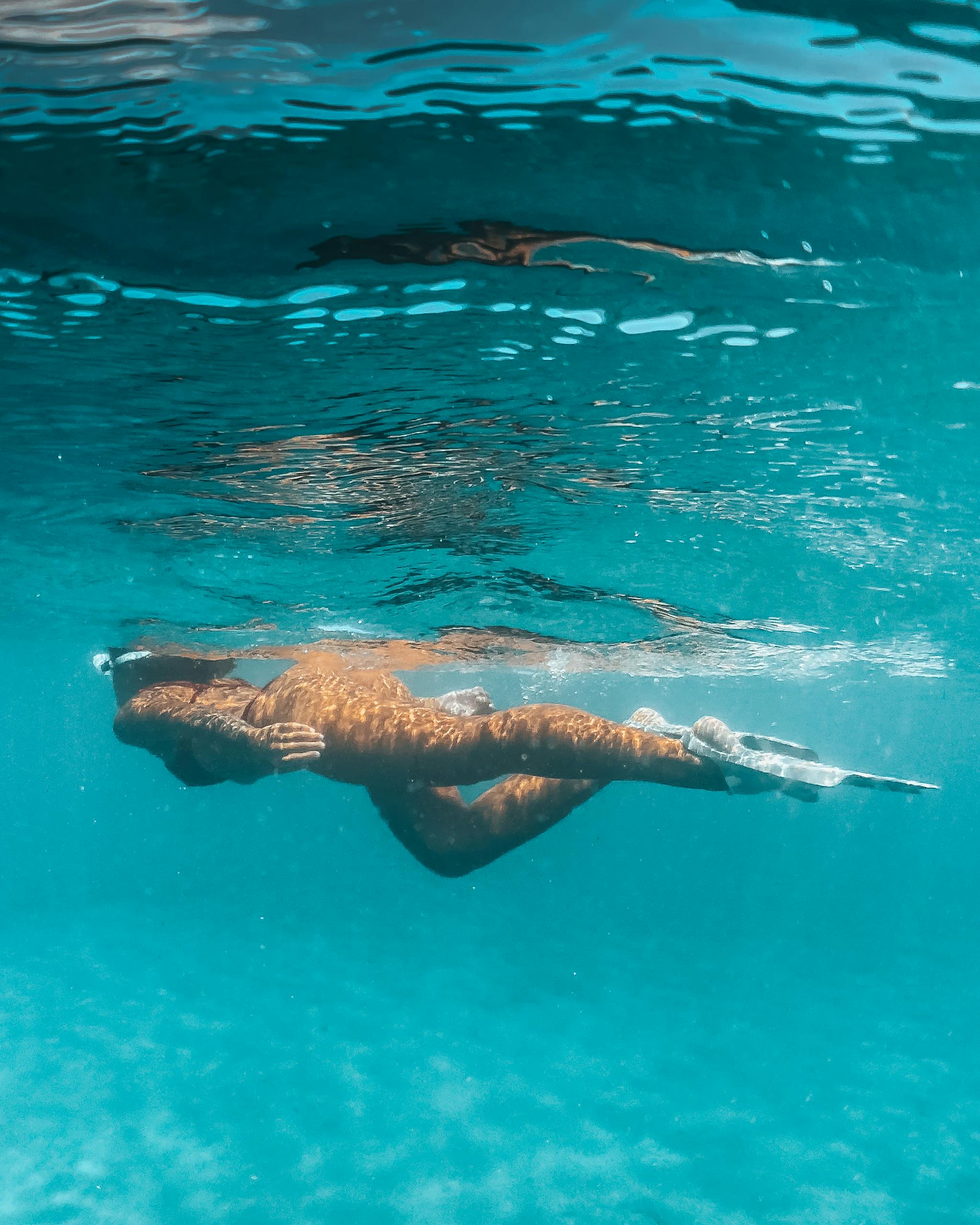 Woman snorkeling underwater in clear blue ocean, showcasing vibrant underwater photography.