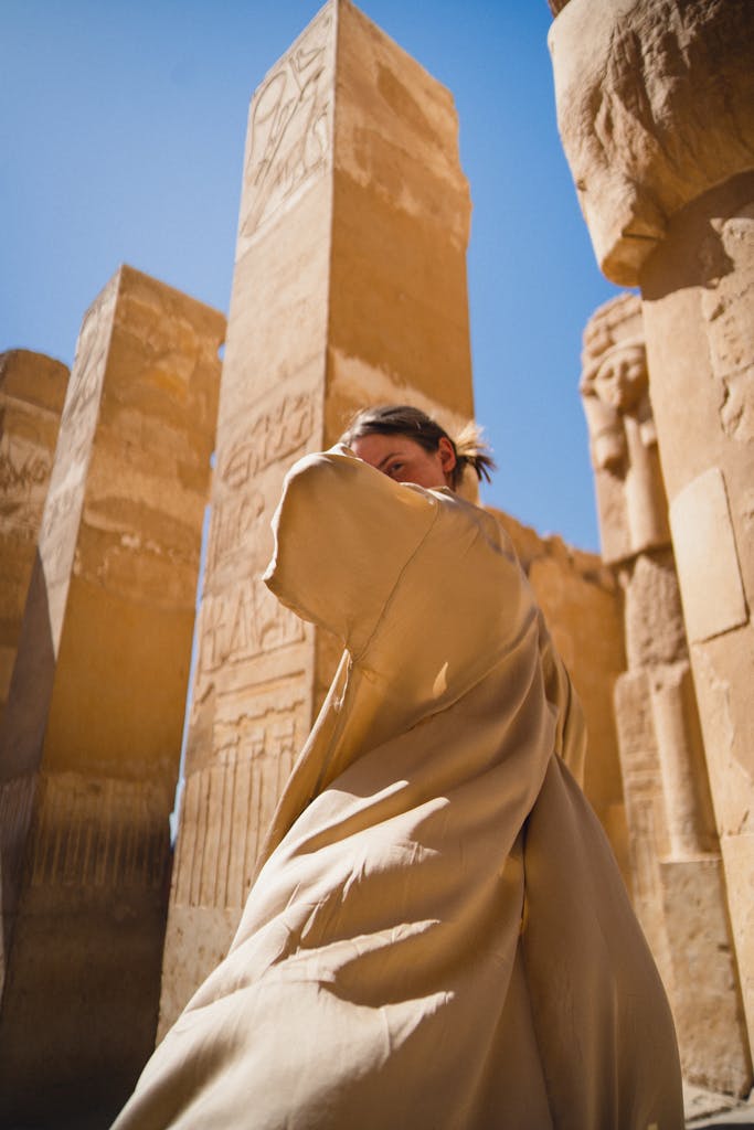 A person wearing beige amidst the ancient ruins of Luxor Temple in Egypt.